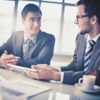 Image of two young businessmen communicating at meeting